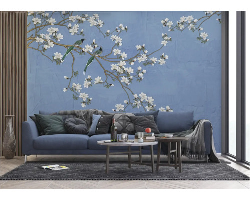 Wohnzimmer mit einer blauen Couch vor einer Wandtapete mit Vogel- und Blütenmotiv
