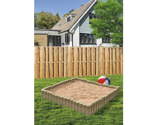 Sandkasten im Garten mit Holzzaun und Wohnhaus