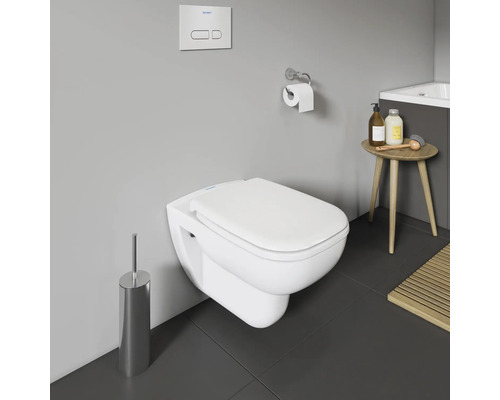 Wandhängendes WC mit Toilettenbürste, Spülknopf, Toilettenpapierhalter und Beistelltisch im Badezimmer.