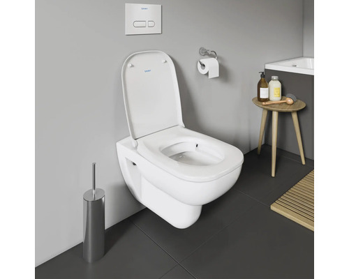 Wandhängendes WC mit Toilettenbürste und Spültaste im Badezimmer.