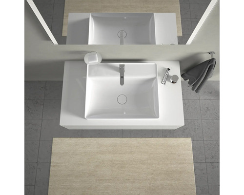 Aufsicht eines Badezimmers mit Waschbecken, Armatur, Seife, Handtuch und Kosmetikprodukten