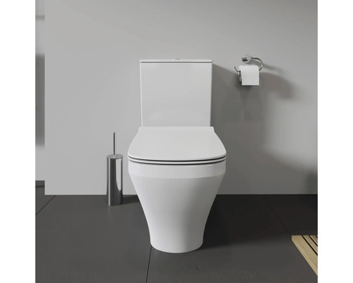 Weisse Toilette mit Toilettenbürste und Toilettenpapierhalter im Badezimmer