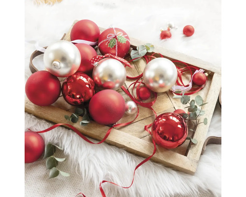 Dekorative Weihnachtskugeln in Rot und Silber auf einem Holztablett.