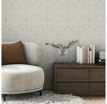 Raumansicht mit floral gemusterter Tapete, Sessel und Kommode