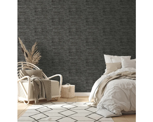 Schlafzimmer mit grauer Struktur-Tapete, Bett, Sessel und Teppich