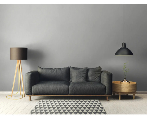 Wohnzimmer mit Sofa, Stehlampe, Pendelleuchte und Beistelltisch auf einem geometrischen Teppich