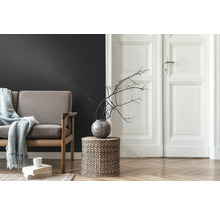 Wohnzimmer mit Sofa, Beistelltisch aus Korbgeflecht, Vase mit Ästen und Holzboden