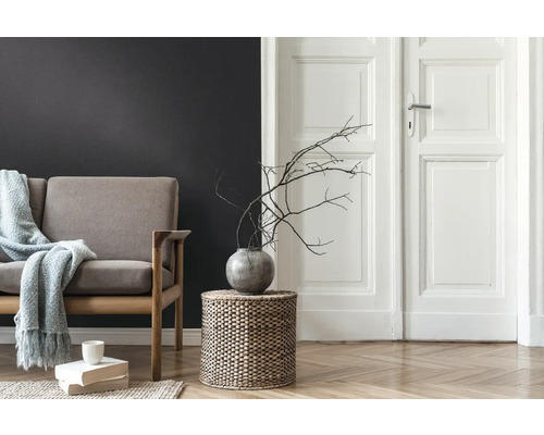 Wohnzimmer mit Sofa, Beistelltisch aus Korbgeflecht, Vase mit Ästen und Holzboden