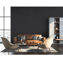 Wohnzimmer mit braunem Ledersofa, zwei Sesseln und einem Regal