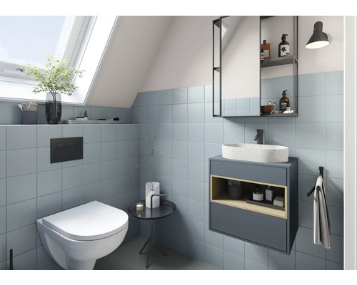 Modernes Badezimmer mit Toilette, Waschtisch und Spiegelschrank unter einem Dachfenster
