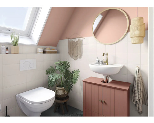 Badezimmer mit Toilette, Waschbecken, Spiegel und Dekorationen unter einem Dachfenster