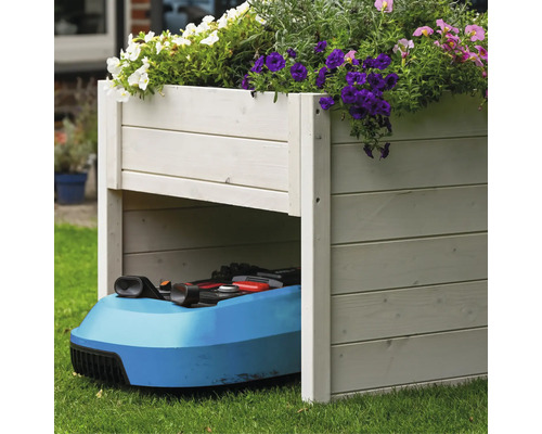 Holzkasten mit Blumen bepflanzt und Rasenmähroboter darunter