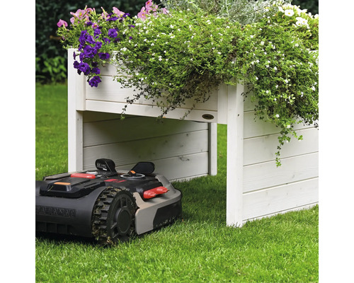 Automatischer Rasenmäher unter einem Hochbeet aus Holz