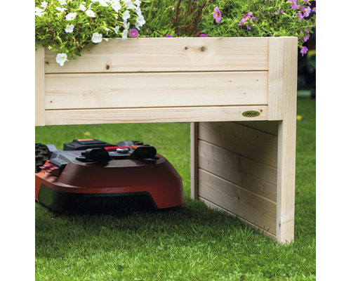 Holz-Hochbeet mit Roboter-Rasenmäher darunter im Garten.
