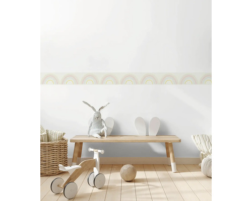 Kinderzimmer mit Holzbank, Laufrad, Spielzeug und Wandbordüre mit Regenbogenmuster