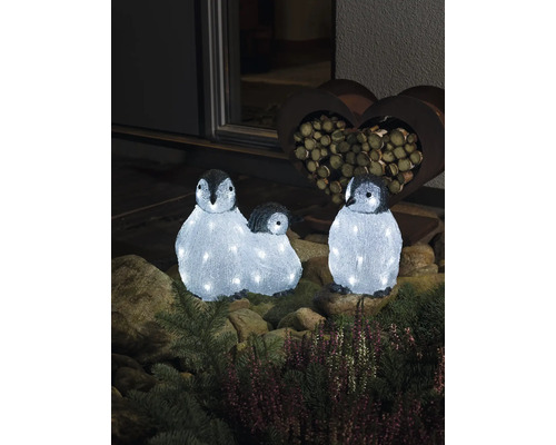 Drei leuchtende Pinguinfiguren als Dekoration im Garten.
