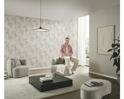 Modernes Wohnzimmer mit gemusterter Tapete, zwei Sesseln, einem Couchtisch und einer Person