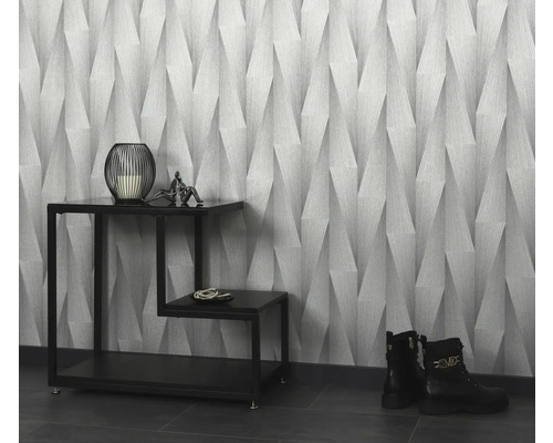 Raumansicht mit gemusterter Tapete, Dekorationen auf einem Beistelltisch und Stiefeln