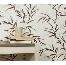 Nahaufnahme einer Wand mit einer Tapete mit Blattmuster, einem Tisch, Büchern und einer Tasse.