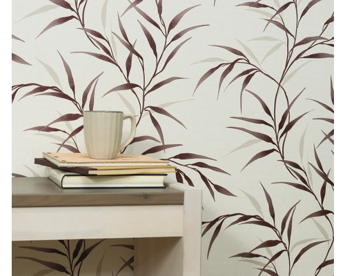 Nahaufnahme einer Wand mit einer Tapete mit Blattmuster, einem Tisch, Büchern und einer Tasse.