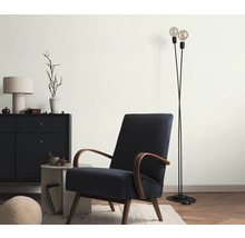 Wohnzimmer mit Sessel, Stehlampe und Kommode für eine gemütliche Atmosphäre.
