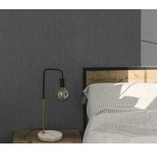 Schlafzimmer mit grauer Struktur-Tapete, Nachttisch und Lampe.