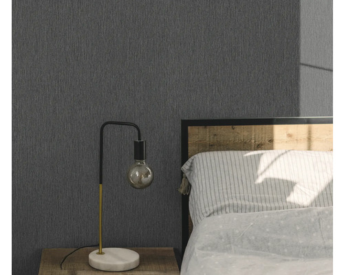 Schlafzimmer mit grauer Struktur-Tapete, Nachttisch und Lampe.