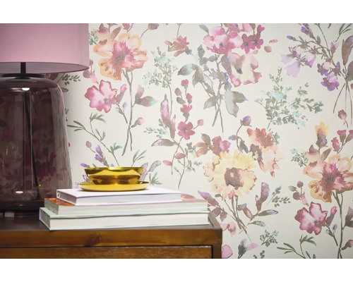 Nahaufnahme einer Wandtapete mit Blumenmuster, ergänzt durch eine Lampe, Bücher und eine Schale auf einem Holzmöbelstück.