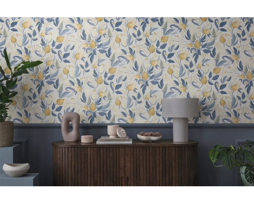 Raumansicht mit floral gemusterter Tapete und Holzkommode mit Dekorationsgegenständen