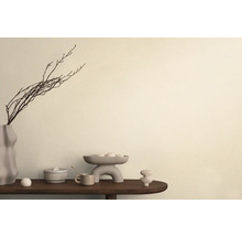 Dekorative Anordnung mit Vase, Zweigen, Schale und Keramikobjekten auf einem Tisch.