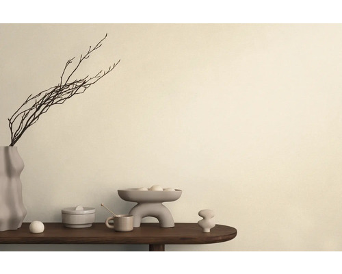 Dekorative Anordnung mit Vase, Zweigen, Schale und Keramikobjekten auf einem Tisch.