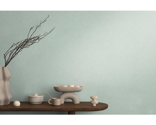 Dekoratives Arrangement auf einem Holztisch vor einer Wand mit Textiltapete