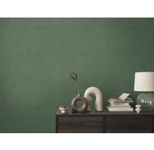 Detailaufnahme einer grünen Textiltapete an einer Wand hinter einem Schrank.