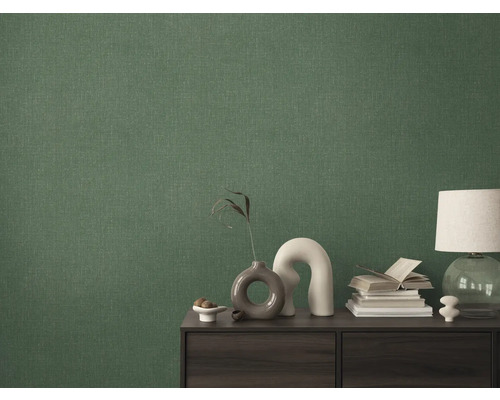 Detailaufnahme einer grünen Textiltapete an einer Wand hinter einem Schrank.