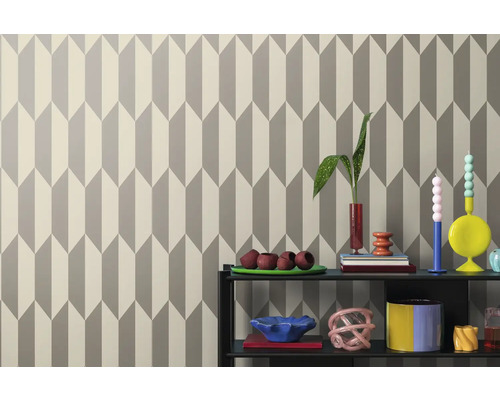 Tapete mit geometrischem Pfeilmuster hinter einem Regal mit Dekorationsgegenständen.