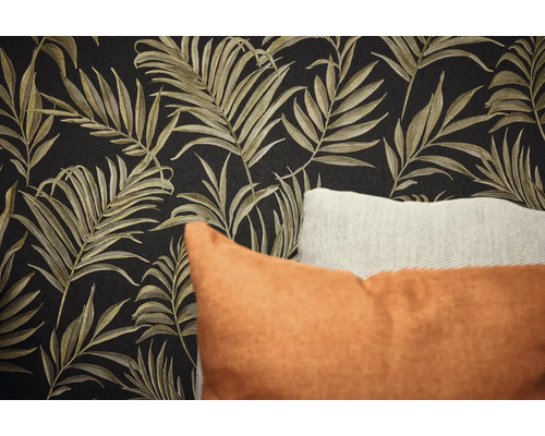 Nahaufnahme einer Wand mit Blättermuster-Tapete und Zierkissen