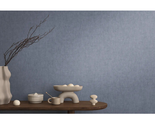 Dekoratives Interieur mit blauer Wandtapete, Tisch mit Dekorationen wie Vase, Schale und Keramikfiguren