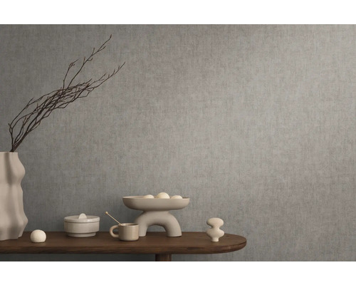 Dekoratives Stillleben mit Vase, Schale und Ziergegenständen auf einem Holztisch vor einer grauen Wand.