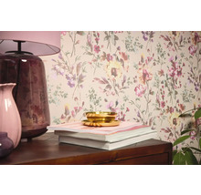 Wohnraumszene mit Blumentapete, Tischleuchte, Vasen, Büchern und Schale.