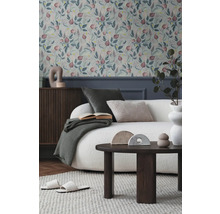 Wohnzimmer mit floral gemusterter Tapete, Sofa, Tisch und Dekorationsgegenständen für ein gemütliches Ambiente.