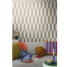 Wohnraum mit geometrischer Tapete in Grau und Weiß hinter einem grauen Sofa