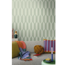 Wohnzimmer mit grauer Couch, Kissen, Decken und einer Wand mit geometrischer Tapete