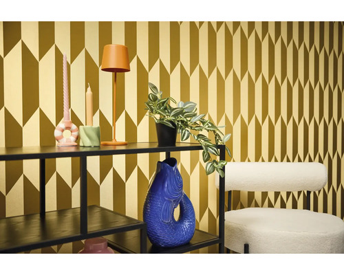 Dekoratives Zimmer mit Regal, Lampe, Kerzen, Pflanze, Vase und Stuhl vor einer gemusterten Tapete