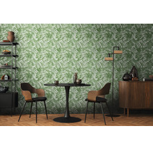 Wohnzimmer mit Esstisch, Stühlen, Regal, Schrank und einer Tapete mit Pflanzenmuster.