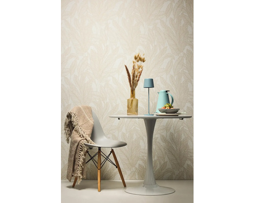 Dekorativer Esstisch mit Stuhl, Tischlampe und Accessoires vor einer gemusterten Tapete