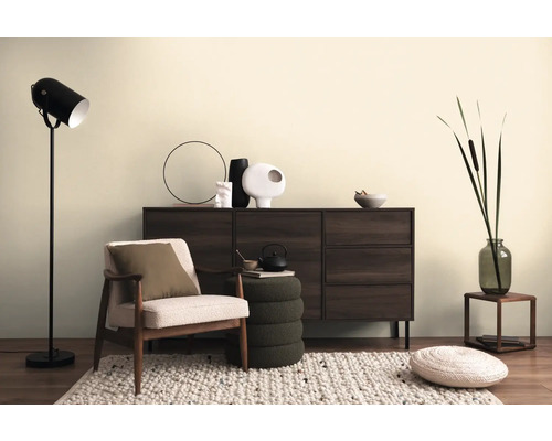 Wohnzimmer-Szene mit Kommode, Sessel, Stehlampe und dekorativen Elementen auf einem Teppich