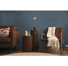 Wohnzimmer mit Sofa, Sessel, Beistelltischen und Dekor auf blau strukturierter Tapete