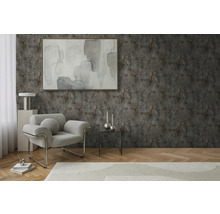 Wohnzimmer mit Sessel, Tisch und Dekoration vor einer strukturierten Wand