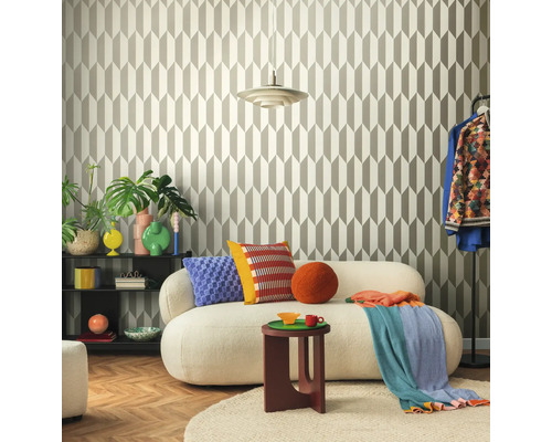 Wohnzimmer mit geometrischer Tapete, Sofa, Beistelltisch und dekorativen Elementen für ein stilvolles Ambiente.