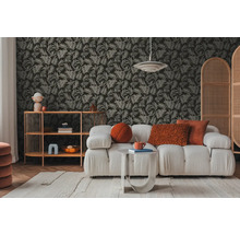 Wohnzimmer mit Sofa, Beistelltisch und Regal vor einer mit Blättern gemusterten Tapete